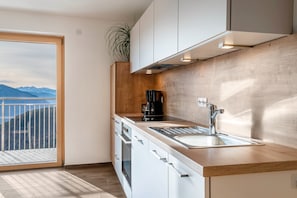 Une cuisine moderne dotée d’une grande fenêtre, de meubles en bois, d’un évier et d’une machine à café.