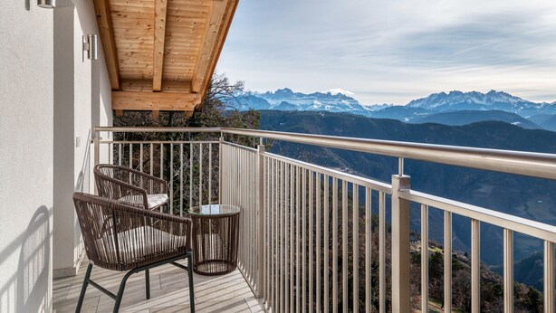 A balcony with a view of snow-capped mountains, a wooden ceiling, and a table with chairs. - Apartment "Reiterhof Gaia" with Mountain View, Private Garden & Wi-Fi (San Genesio Atesino)