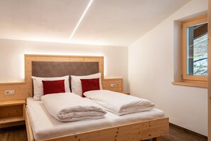 Un dormitorio con cama de madera, dos mesitas de noche, una ventana con vistas y un cabecero.