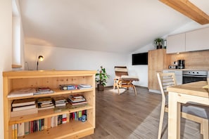 Una cocina moderna con armarios de madera, una mesa de comedor y una estantería llena de libros.