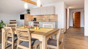 Eine moderne Küche mit Holzschränken, einem Esstisch mit Stühlen und Pendelleuchten.