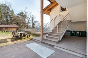 Un espacio al aire libre cubierto con una mesa de picnic y bancos, una escalera y vistas a árboles.