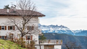 Ein weißes Gebäude mit einem Balkon mit Blick auf eine gebirgige Landschaft.