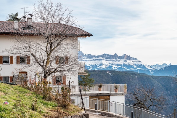 Un edificio blanco con balcón que da a un paisaje montañoso.