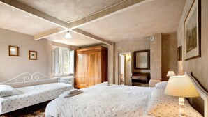 A bedroom with two beds, a wooden wardrobe, a mirror, and a lamp.