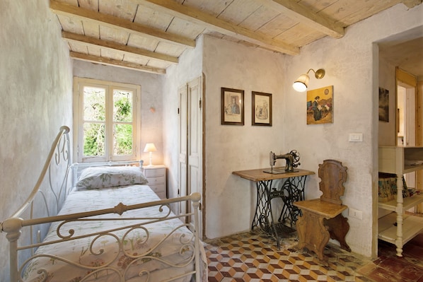 A bedroom with a bed, a sewing machine, a table, and a chair.
