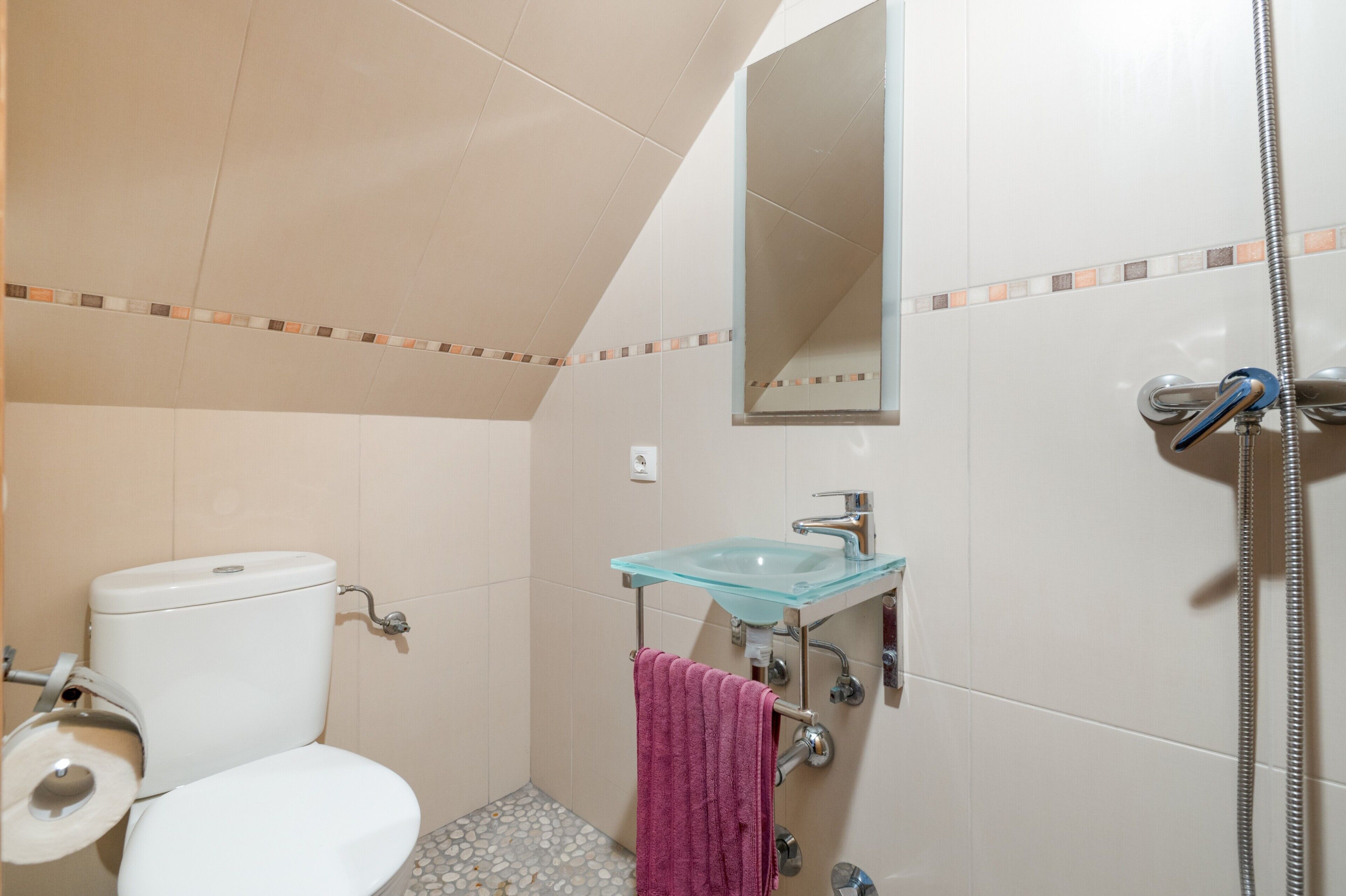 Une salle de bain comprenant des toilettes, un lavabo en verre, une douche et un porte-serviettes.