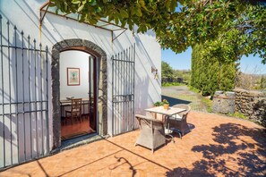 A patio with a table and chairs, a stone wall, and a gate.