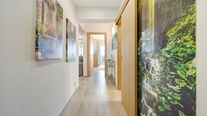 A hallway with a wooden floor, a large painting of a waterfall, and a door at the end. - Holiday Apartment "Karol Vaz" with Balcony, Shared Pool & Wi-Fi (Portimão)