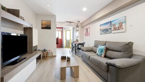 A modern living room with a flat-screen TV, a sofa, a coffee table, and artwork on the walls. - Holiday Apartment "Karol Vaz" with Balcony, Shared Pool & Wi-Fi (Portimão)