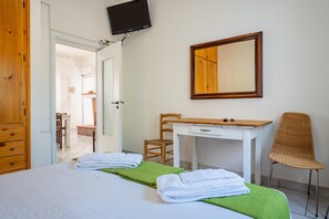 Een hotelkamer met een bed, bureau, stoel, spiegel en televisie.