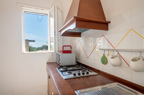 A kitchen with a gas stove, a window, and a tiled backsplash.
