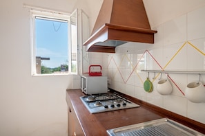A kitchen with a gas stove, a window, and a tiled backsplash.
