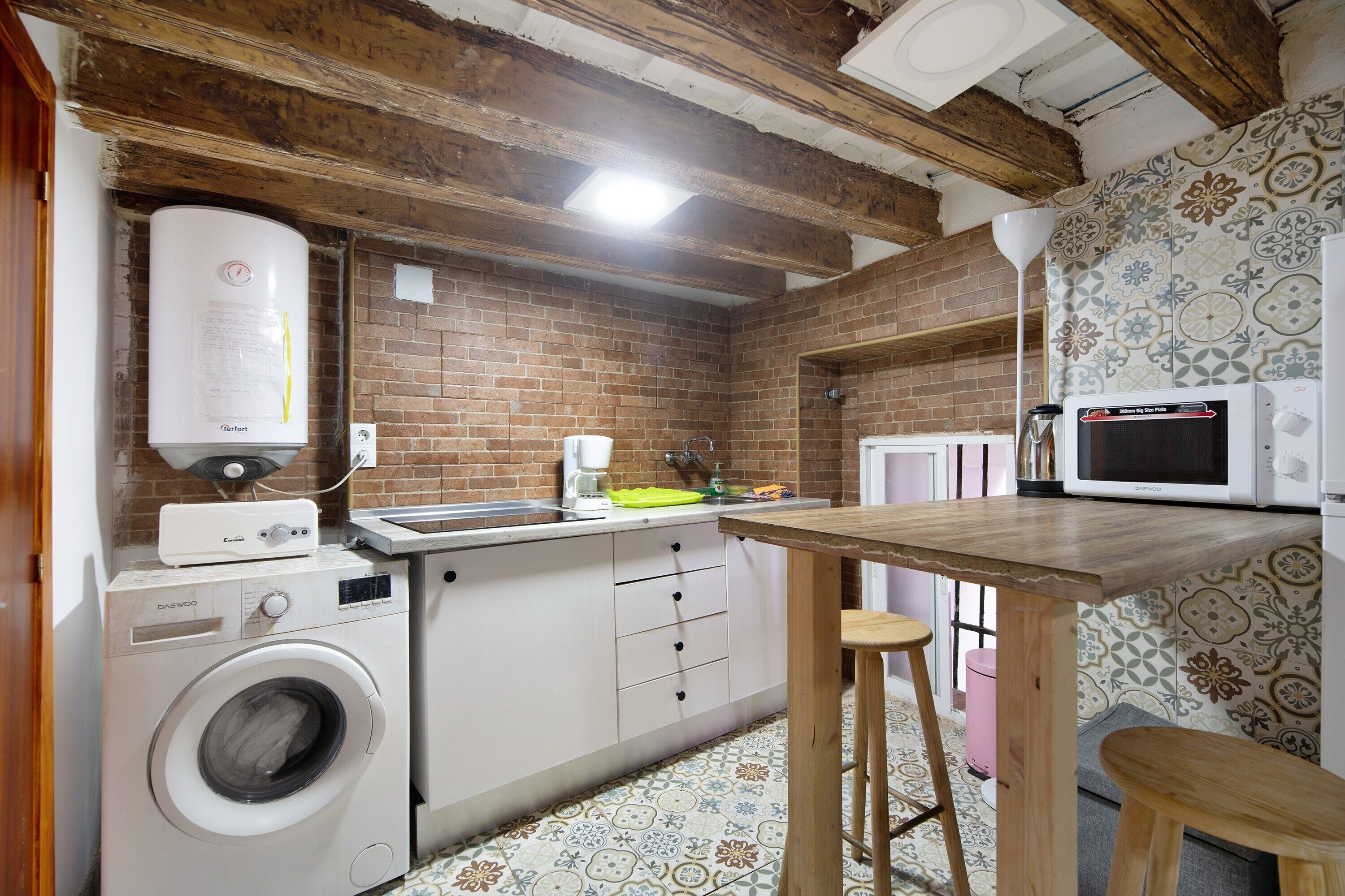 A compact kitchen with a washing machine, a microwave, and a sink.