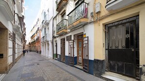 Una estrecha calle adoquinada bordeada por edificios de varios pisos con balcones, puertas y ventanas.