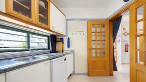 A kitchen with a dishwasher, a window, and a door leading to another room.