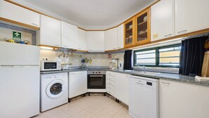 A compact kitchen with a washing machine, oven, microwave, and dishwasher.