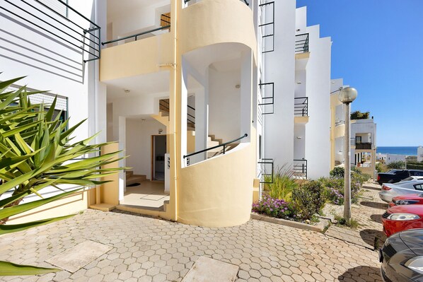 A modern building with a spiral staircase, a paved entrance area, and a view of the sea.