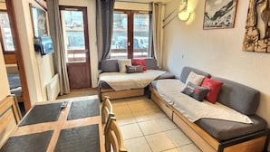 Et lille værelse med en seng, en sofa, et spisebord og et fjernsyn.
