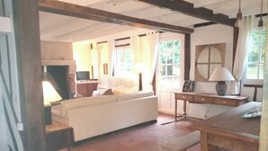 Een gezellige woonkamer met een witte bank, een houten tafel en een open haard.