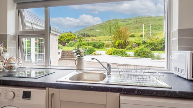 A kitchen with a large window, a washing machine, and a microwave.