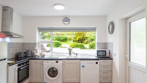 Een kleine keuken met een wasmachine, een magnetron en een spoelbak.