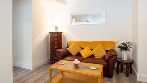 Een woonkamer met een bruine leren bank, een houten salontafel, een bijzettafeltje van hout en een lamp.