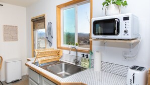 Eine Küche mit Mikrowelle, Toaster, Spüle und einem Fenster mit Blick.