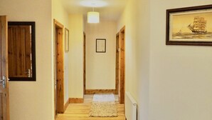 A narrow hallway with wooden doors, a white carpet, and a framed picture on the wall.
