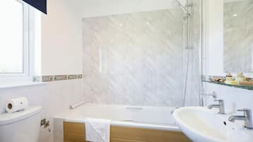 Ein modernes Badezimmer mit einer Duschwand aus Marmor, einer Badewanne und einem Waschbecken.