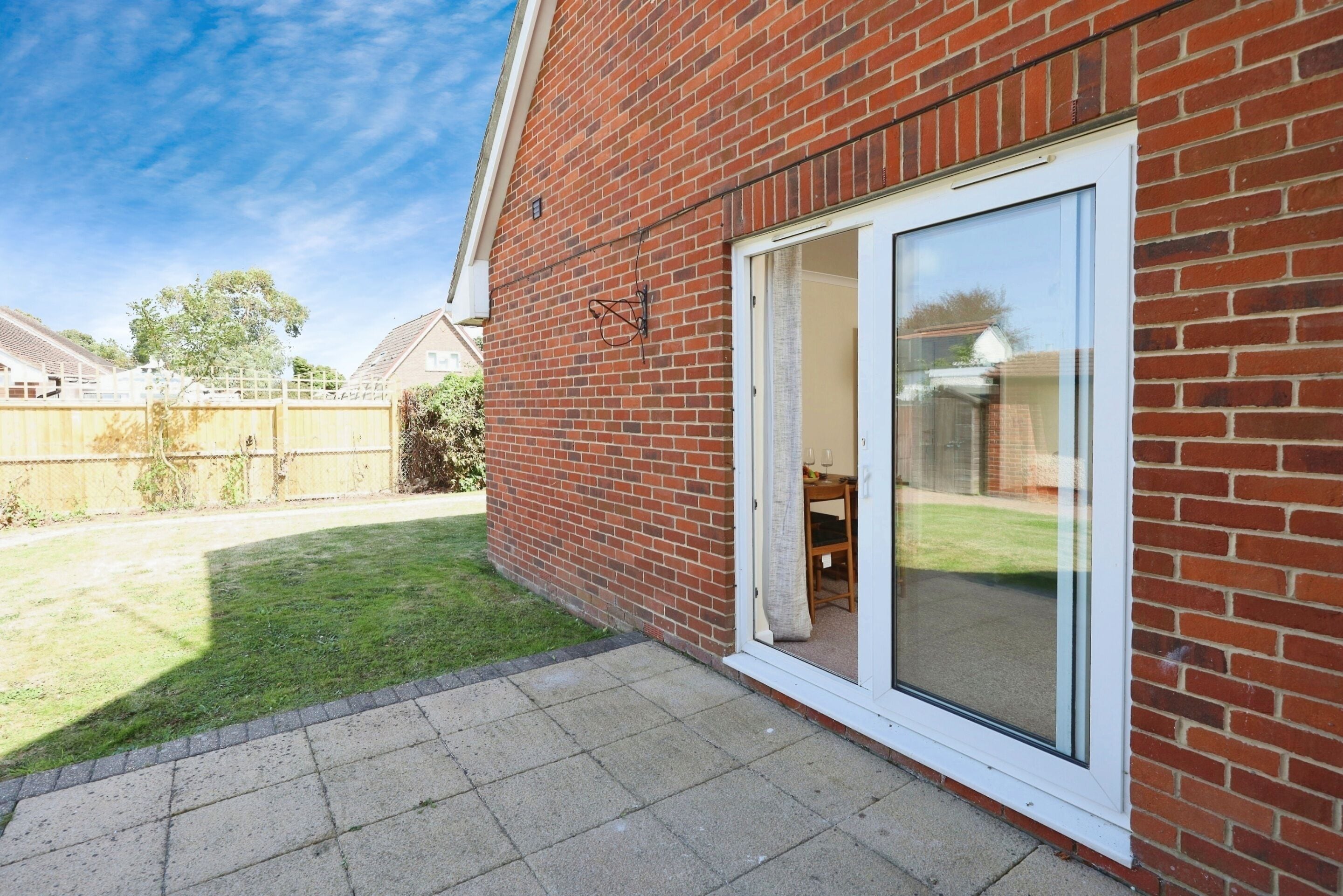 A brick house with a sliding glass door leading to a patio area.