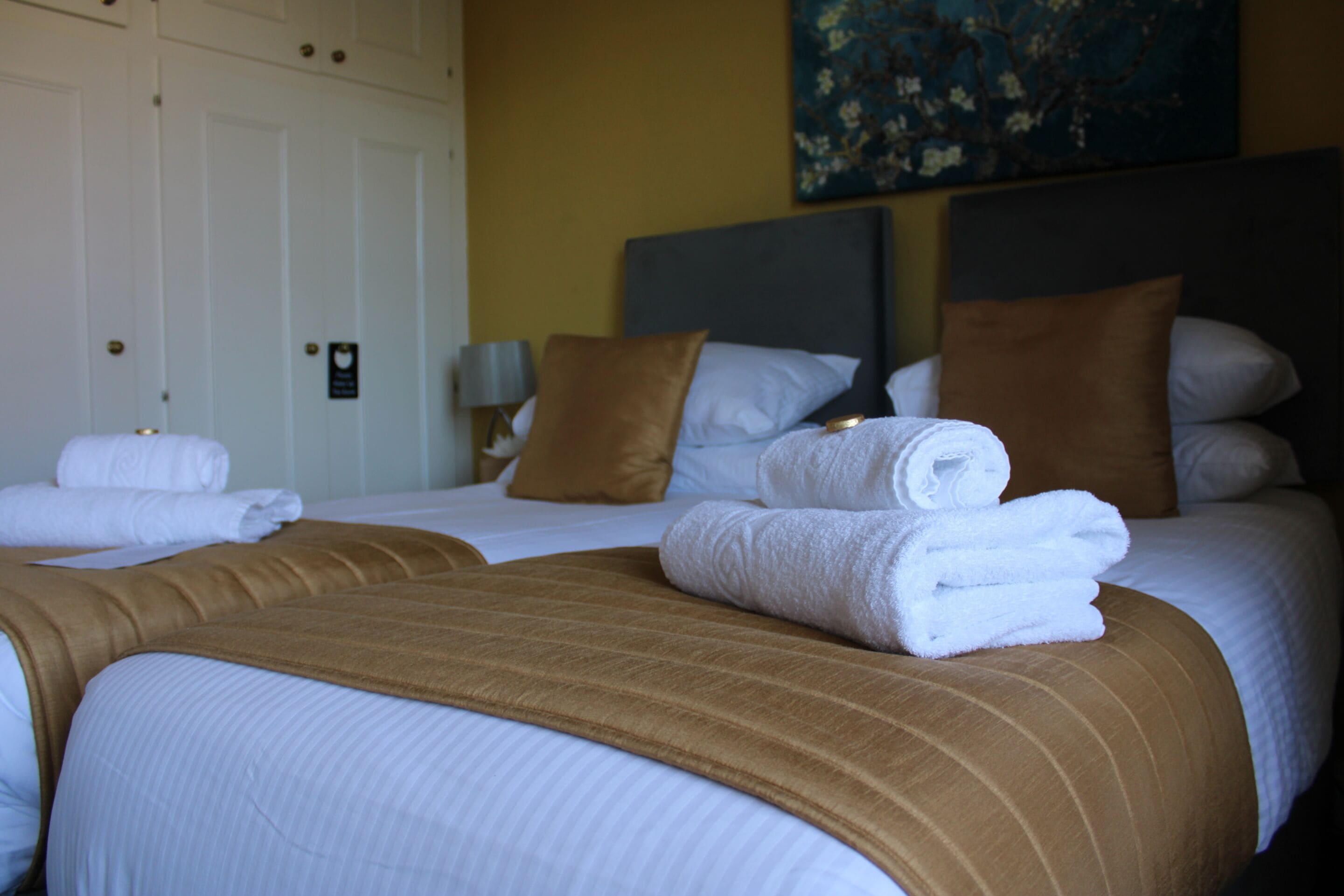 Una habitación de hotel con una cama bien hecha, una manta marrón y un cuadro en la pared.