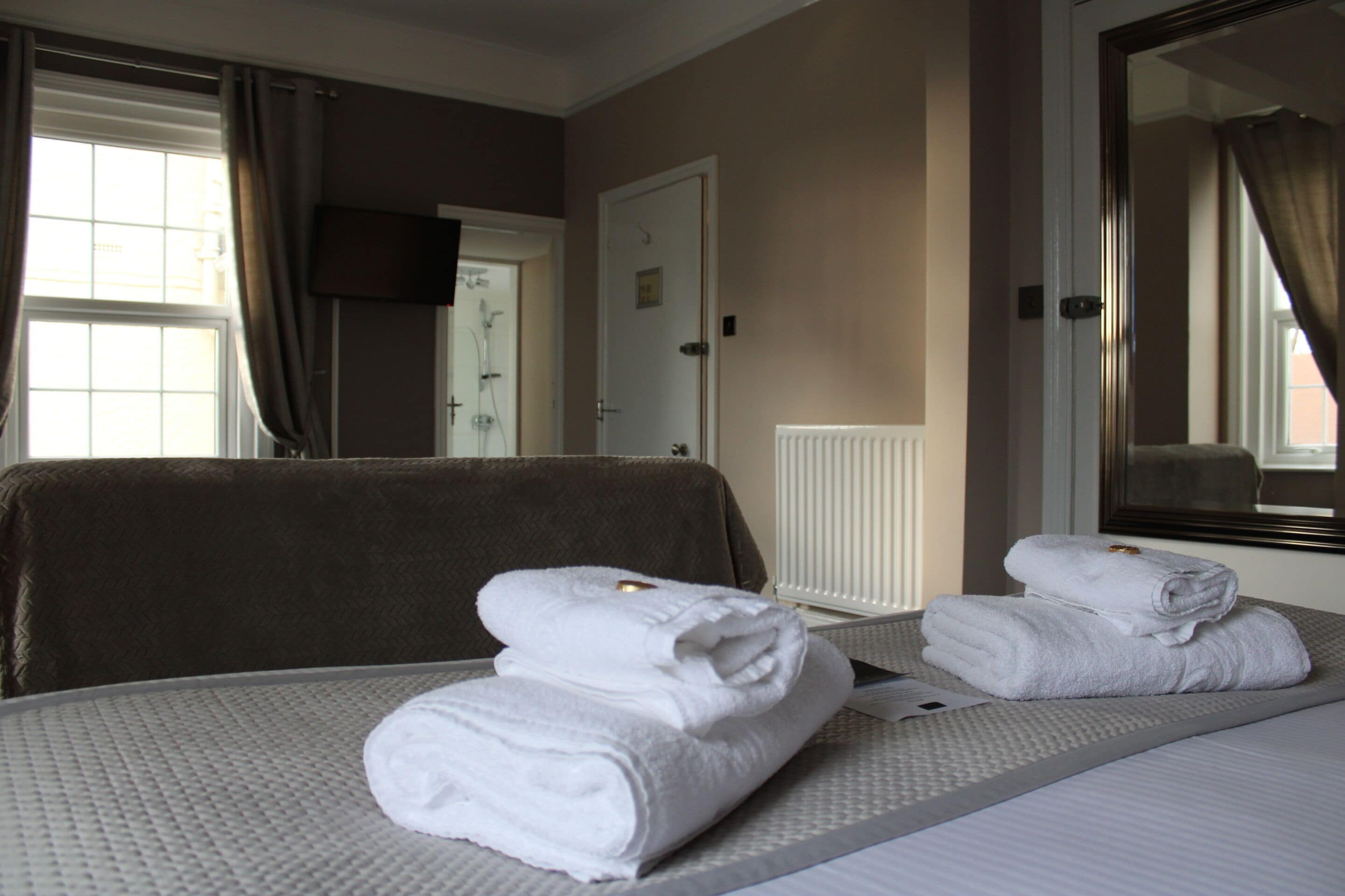 Une chambre d’hôtel avec deux lits, une télévision et une fenêtre avec des rideaux.