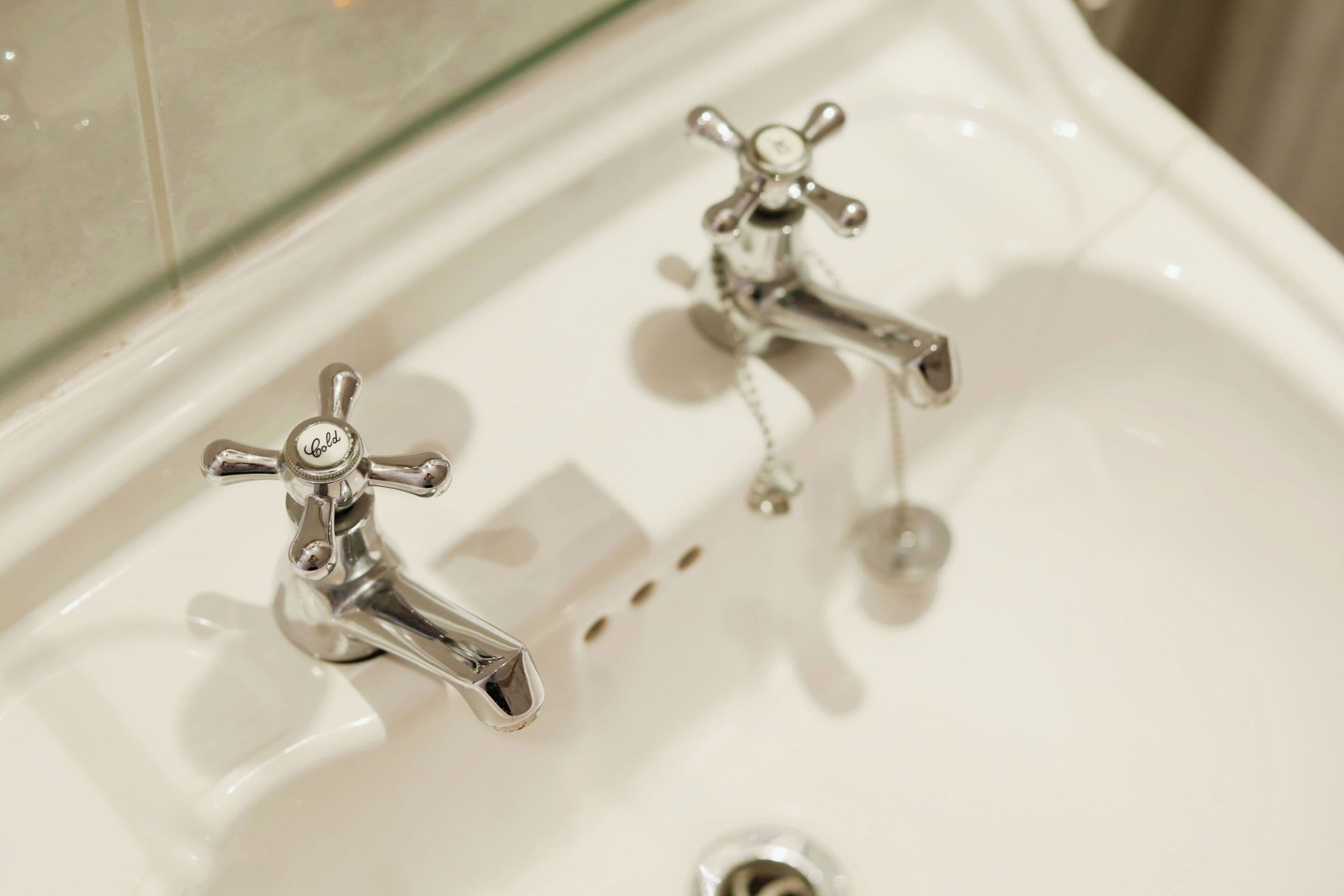 A bathroom sink with two chrome faucets and a mirror above it.