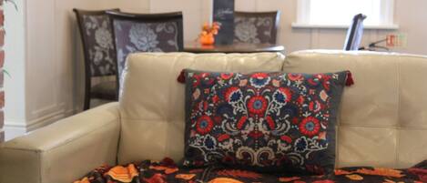 A living room with a beige sofa, a patterned throw blanket, and a floral pillow.