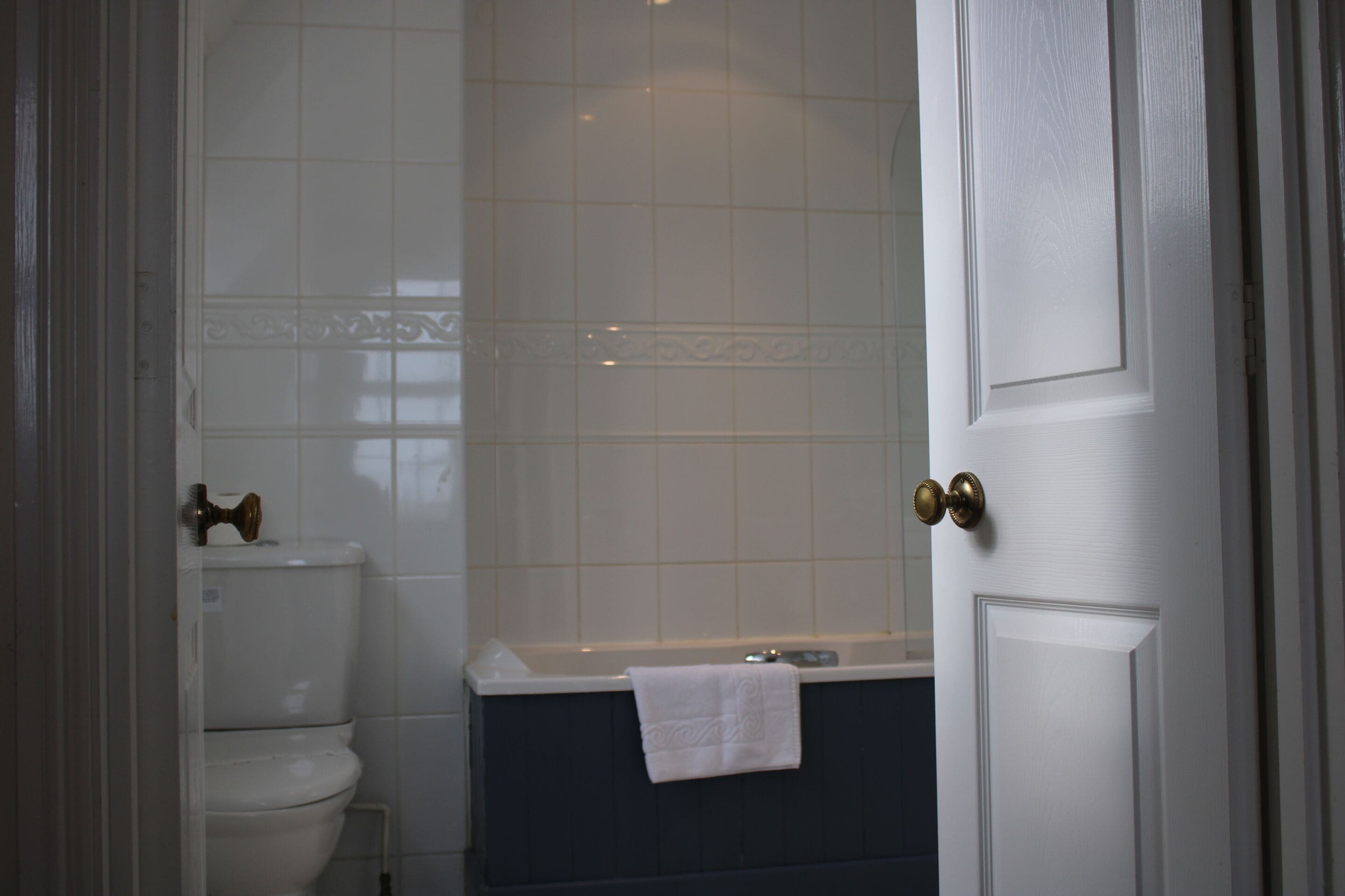 A bathroom with a toilet, bathtub, and a towel hanging on the wall.