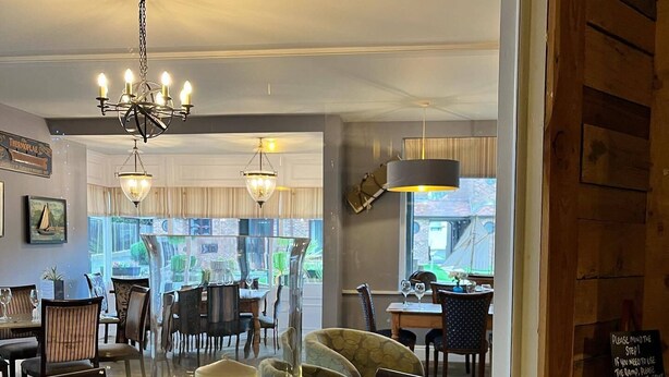 A dining area with a large mirror reflecting the room, a chandelier, and a decorative candle centerpiece. - The Birdham Hotel & Restaurant (Bembridge)