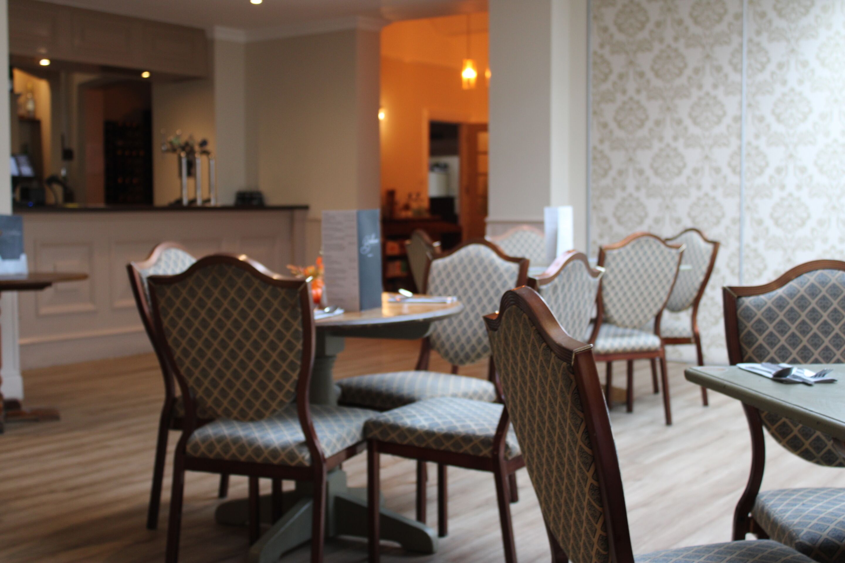 A dining area with patterned upholstered chairs and a round table.