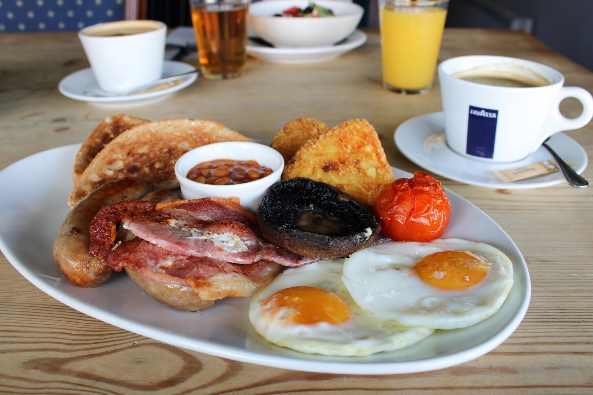 Un plato de desayuno con huevos, tocino, champiñones, tostadas y frijoles.