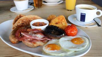 Un plato de desayuno con huevos, tocino, champiñones, tostadas y frijoles.