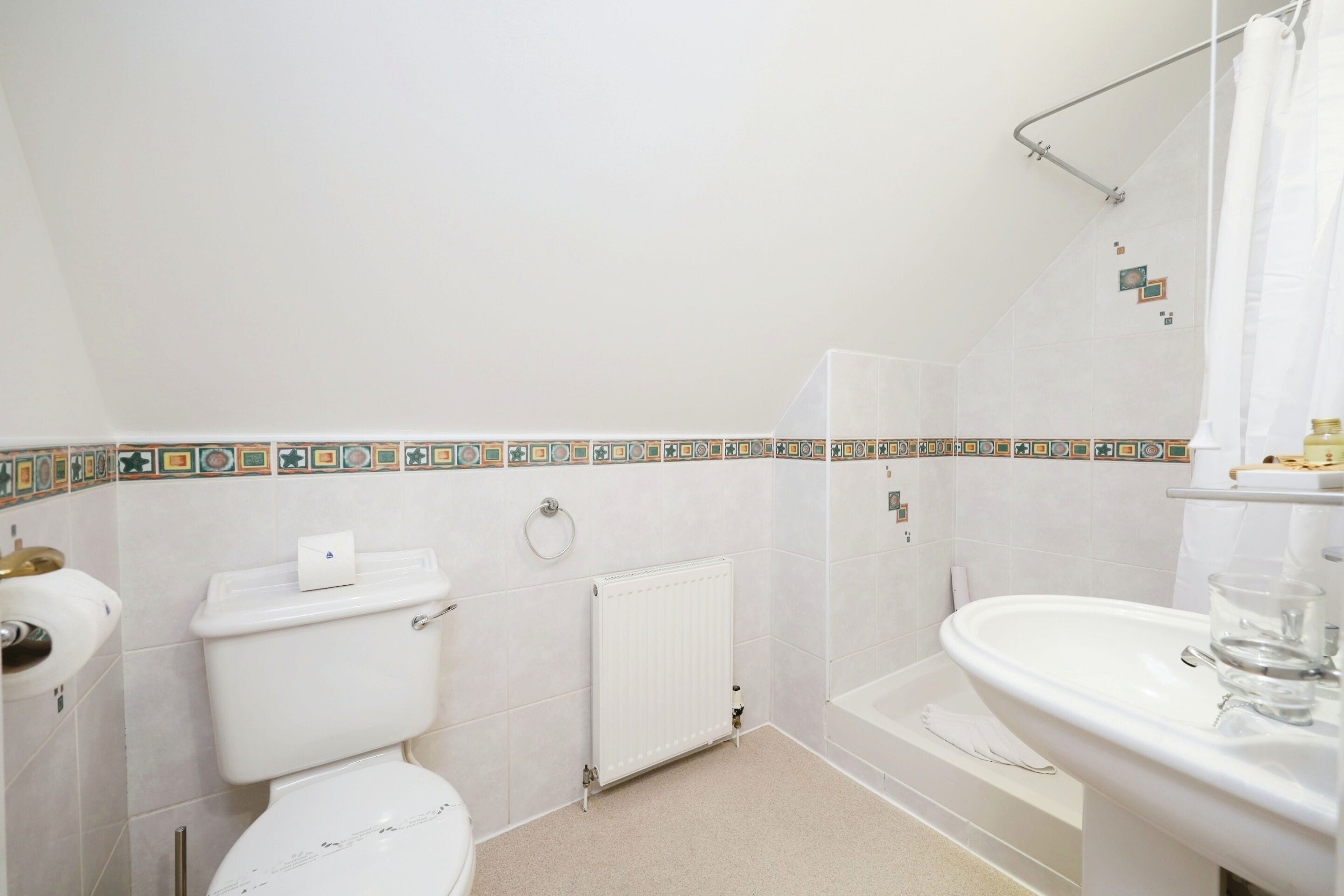 A bathroom with a toilet, a radiator, a shower, and a sink.