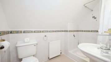 A bathroom with a toilet, a radiator, a shower, and a sink.