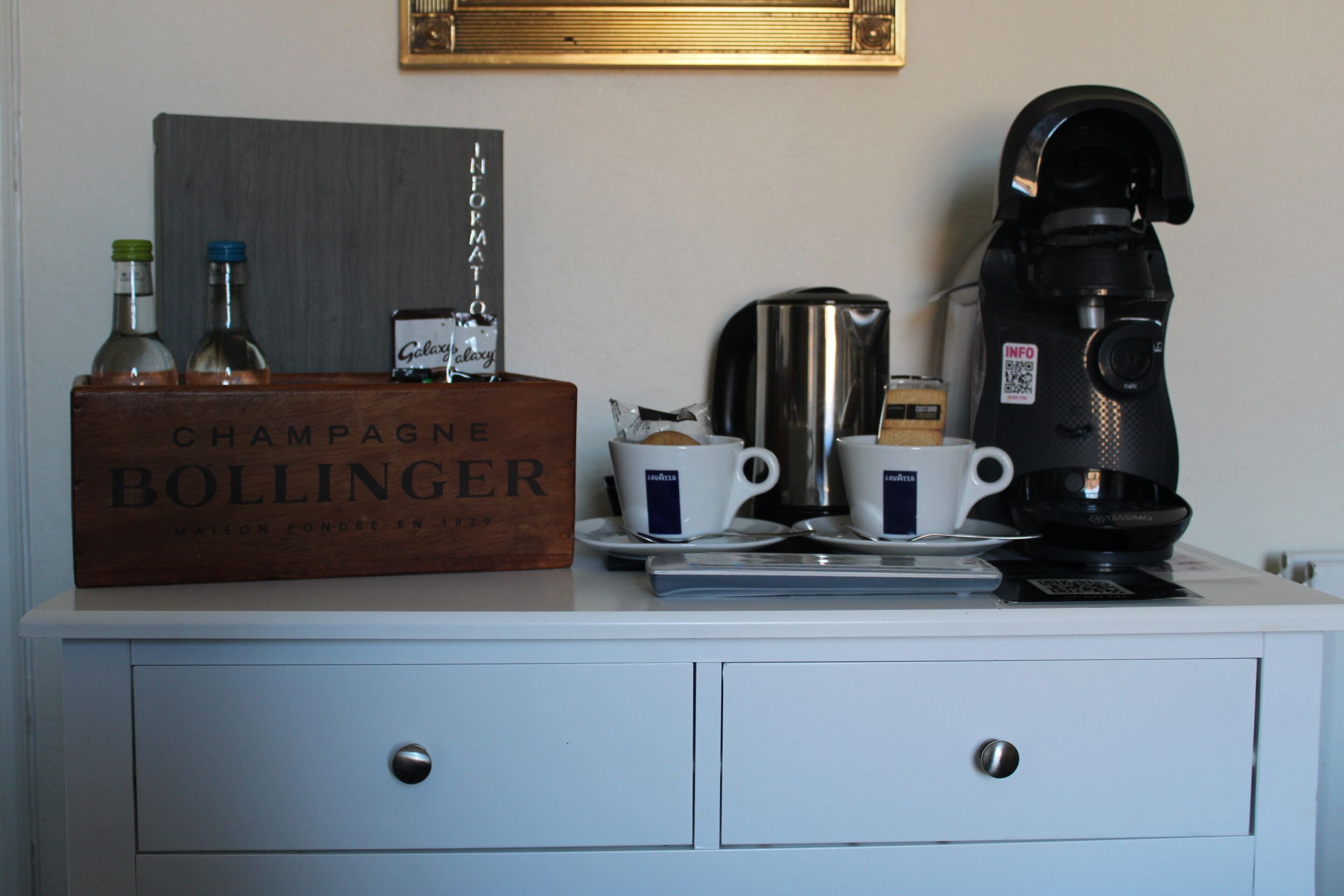 Un mini-bar comprenant une bouteille de champagne, deux verres, une machine à café et une bouilloire.