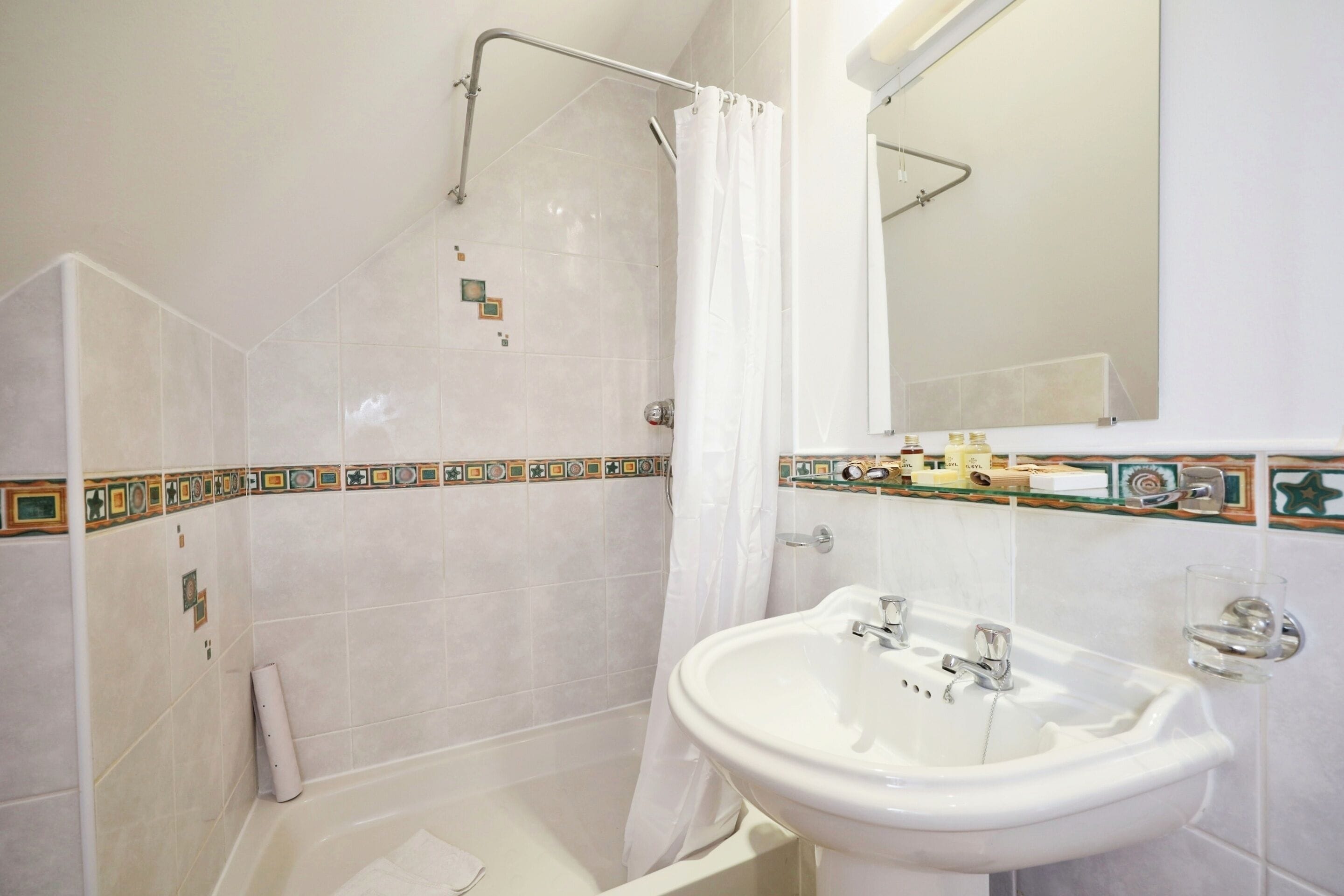 Un baño con ducha, lavabo y espejo.