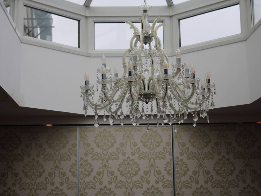 Un candelabro en una habitación con papel tapiz estampado y un tragaluz.