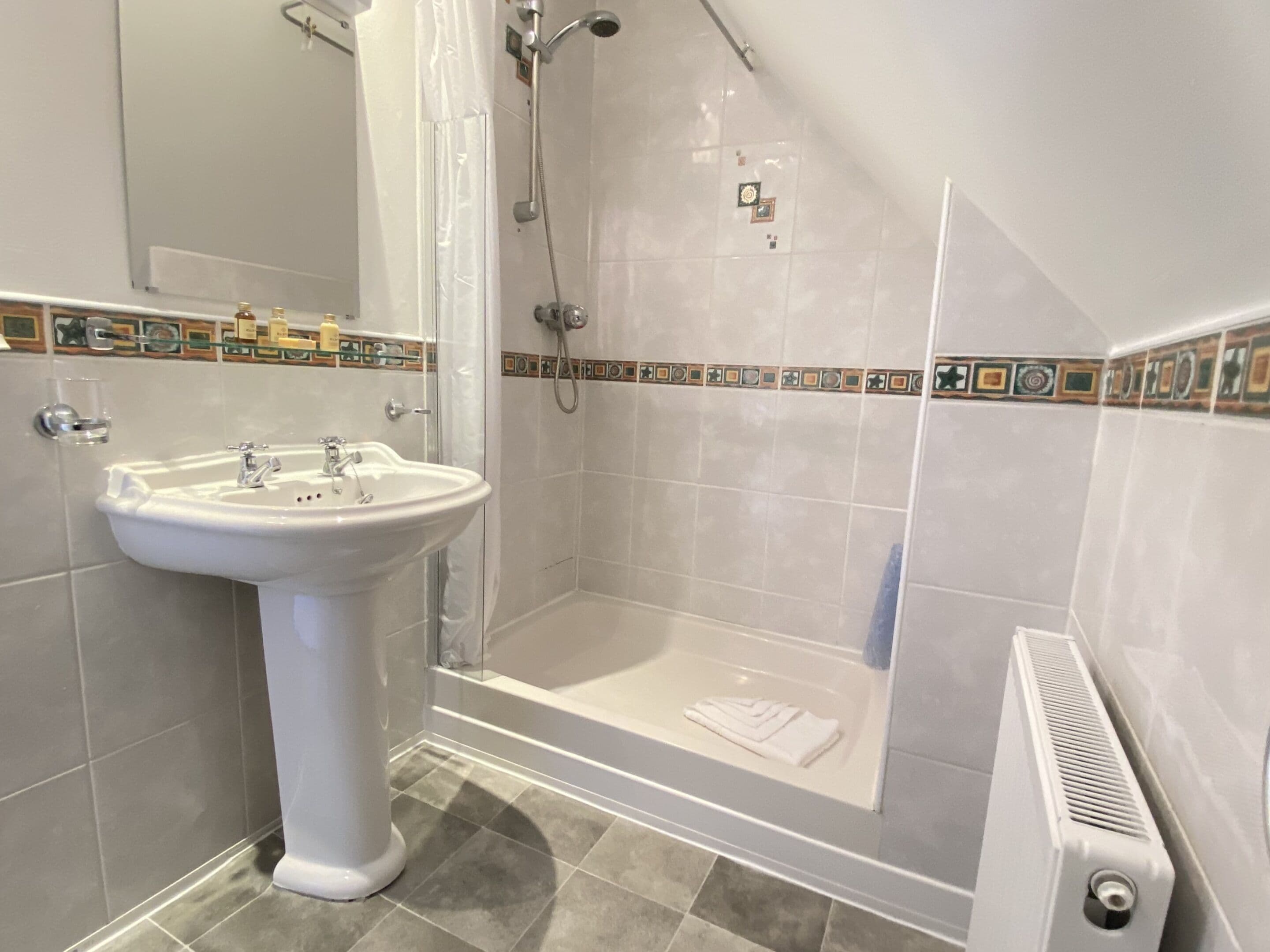 Un baño con lavamanos pedestal, ducha y bañera.