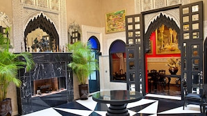 A lobby with a black and white checkered floor, ornate arches, a fireplace, and a round table. - Riad Dar Chrifa (Rabat)