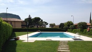 Une piscine rectangulaire à l’eau d’un bleu limpide, entourée d’une pelouse bien entretenue et d’un chemin de pierre menant à la piscine.