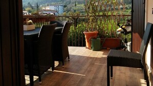 Une terrasse en bois avec des meubles d’extérieur, un grand parasol et des plantes en pot.