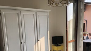 Une chambre à coucher avec un lit, une armoire, un téléviseur posé sur une petite table et une vue sur l’extérieur.